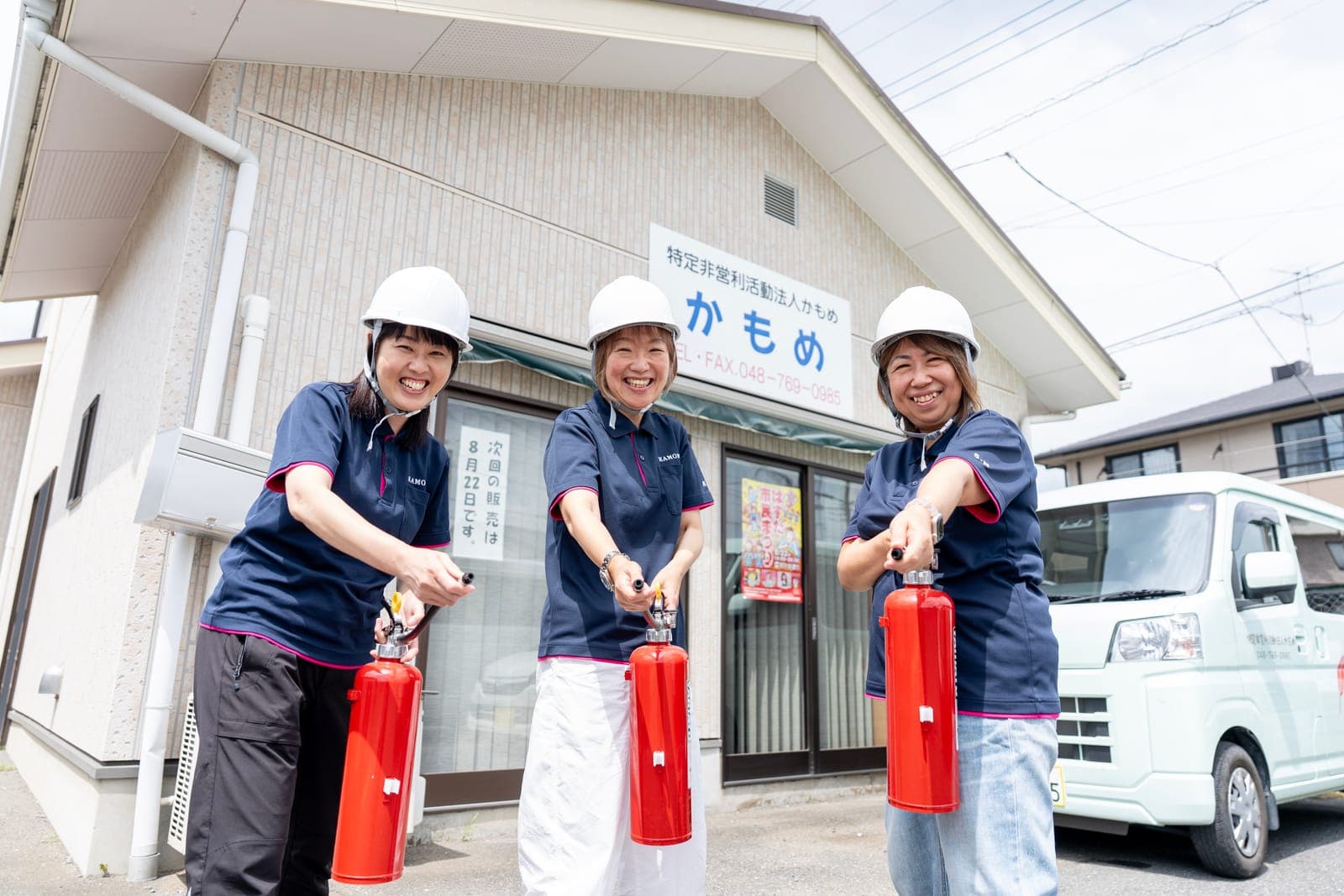 事業所の前で消火器を構えて防災訓練をする3名の女性職員
