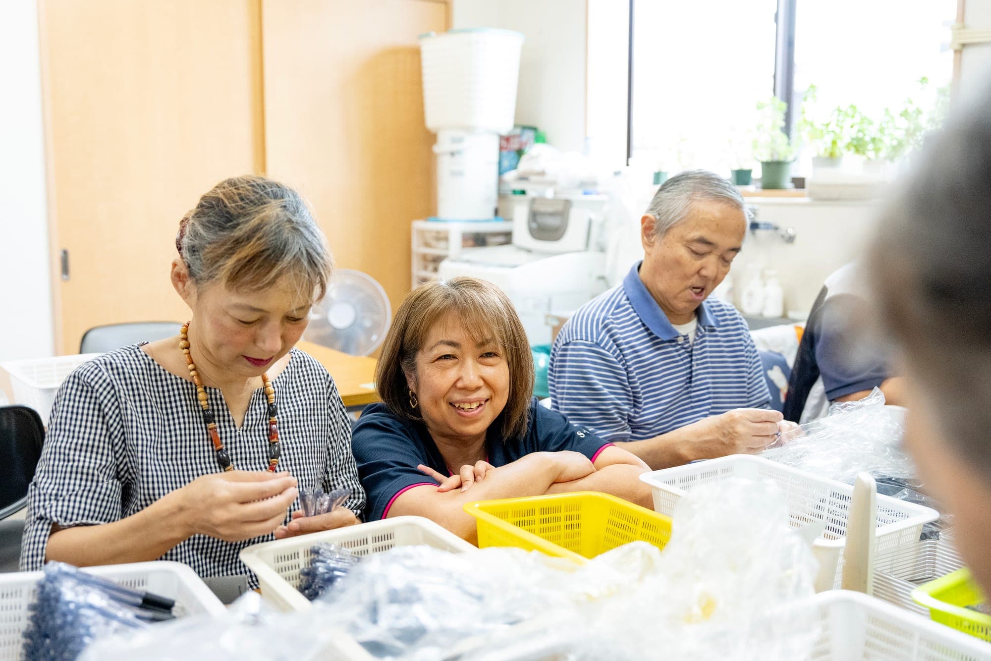 作業台を囲んで内職作業をするご利用者様とスタッフ